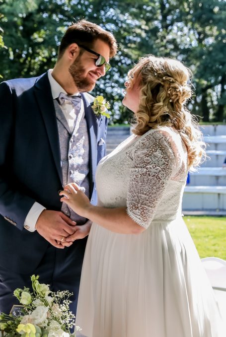 Braut und Bräutigam stehen sich romantisch gegenüber, umgeben von Natur.
