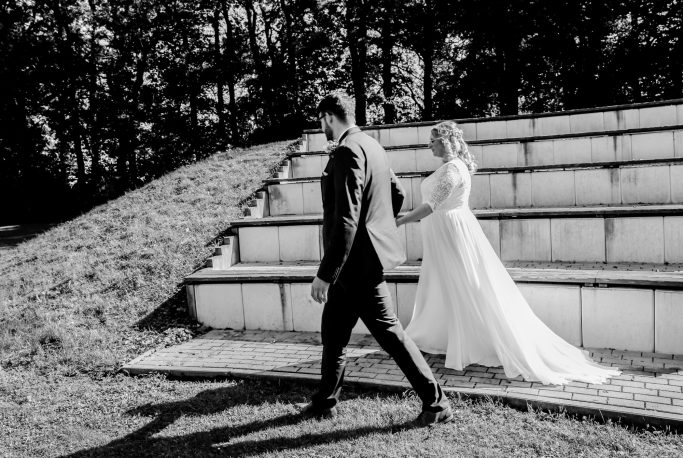 Braut und Bräutigam gehen Hand in Hand eine Treppe im Freien hinunter.
